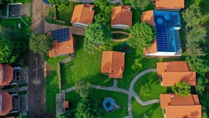 Vista aérea de una zona residencial con varias casas, una piscina y una estructura circular de piedra.