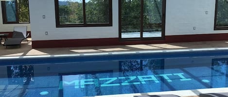 Una piscina techada, camas de piscina con cargo, sombrillas