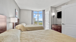 A hotel room with two beds, a TV, a dresser, and a window with a view of the beach. - 1st Rate Views & Amenities - Ritzy Oceanfront Family Resort w/pools, pier restaurant/bar in Ocean Dr (North Myrtle Beach)