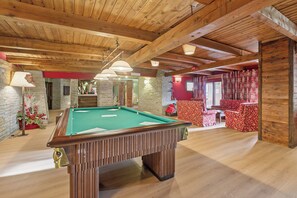A pool table in a room with wooden beams, stone walls, and red upholstered chairs. - Sises Lodge - 27D Sestriere (Sauze di Cesana)