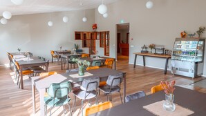 A modern dining area with multiple tables and chairs, a coffee machine, and a refrigerator. - Hotel Kaldi (Dalvik)