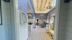 A hallway with patterned flooring leading to a dining area with a blue and white color scheme. - Villages, 3bed- 2.5ba waterfrnt+ golf cart- all bedrooms have king beds! (Wildwood)