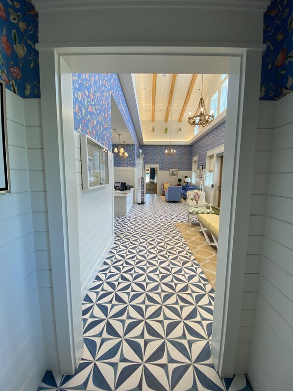 A hallway with patterned flooring leading to a dining area with a blue and white color scheme.