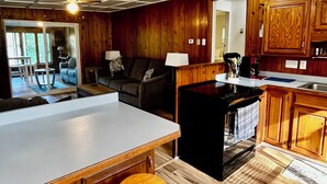 A spacious kitchen with wooden cabinets, a central island with stools, and a dining area with a large table. - Lakefront year round home, gorgeous views, central location (Remsen)