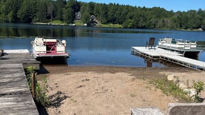 A lakeside dock with a boat, a wooden pier, and a chair. - Lakefront year round home, gorgeous views, central location (Remsen)