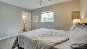 Een slaapkamer met een bed, een plafondventilator, een raam en een nachtkastje met een lamp.