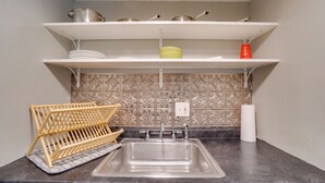 Een keuken met een roestvrijstalen spoelbak, witte planken erboven en een decoratieve spatwand.