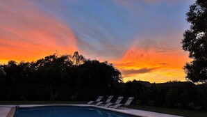 Una piscina con sillas de descanso y vistas al atardecer.