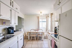 A compact kitchen with white cabinets, a coffee maker, a sink, and a dining area with two chairs. - Perfect Notre Dame Weekend Home, 0.8 Miles to ND! (South Bend)