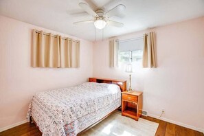 A bedroom with a bed, a nightstand, a lamp, a ceiling fan, and a window with curtains. - Perfect Notre Dame Weekend Home, 0.8 Miles to ND! (South Bend)