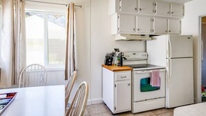Eine kleine Küche mit weißen Schränken, einem Herd und einem Kühlschrank.