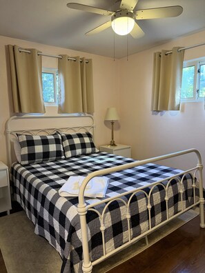 A bed with a checkered bedspread, a bedside lamp, and a ceiling fan.