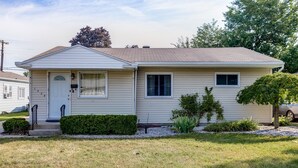 Ein eingeschossiges Haus mit Veranda, kleinem Vorgarten und Garage.