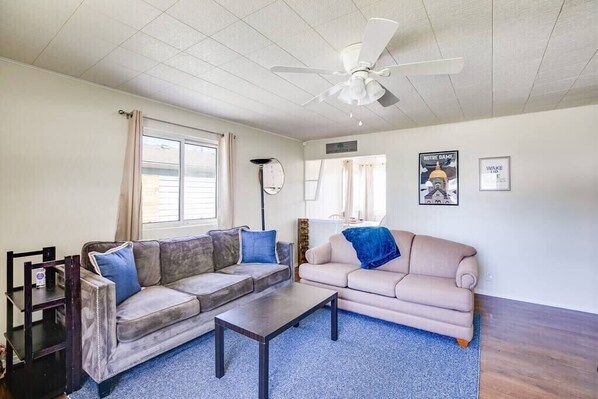 A living room with two couches, a coffee table, a ceiling fan, and a window with curtains. - Perfect Notre Dame Weekend Home, 0.8 Miles to ND! (South Bend)