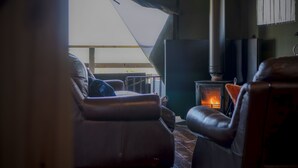 Ein gemütliches Wohnzimmer mit Ledersofas, einem Kamin und Blick ins Freie.