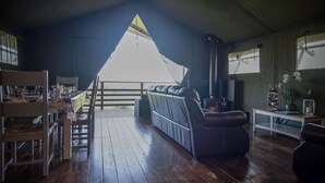 Ein gemütliches Zimmer mit Holzboden, einer Couch, einem Esstisch mit Stühlen und Blick durch ein Dreiecksfenster.