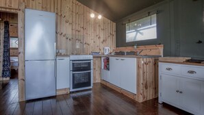 Eine Küche mit Holzwandverkleidung, einem Kühlschrank, einem Backofen, einer Spüle und Schränken.