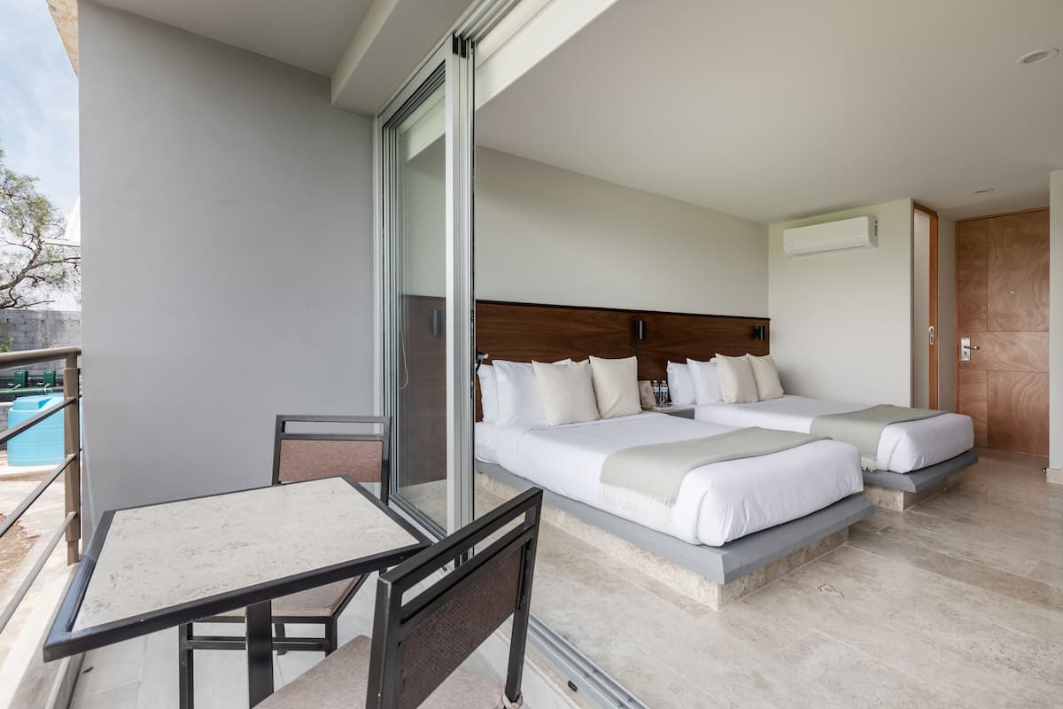 A modern hotel room with a balcony, a bed with two pillows, a bedside table, and a large window.