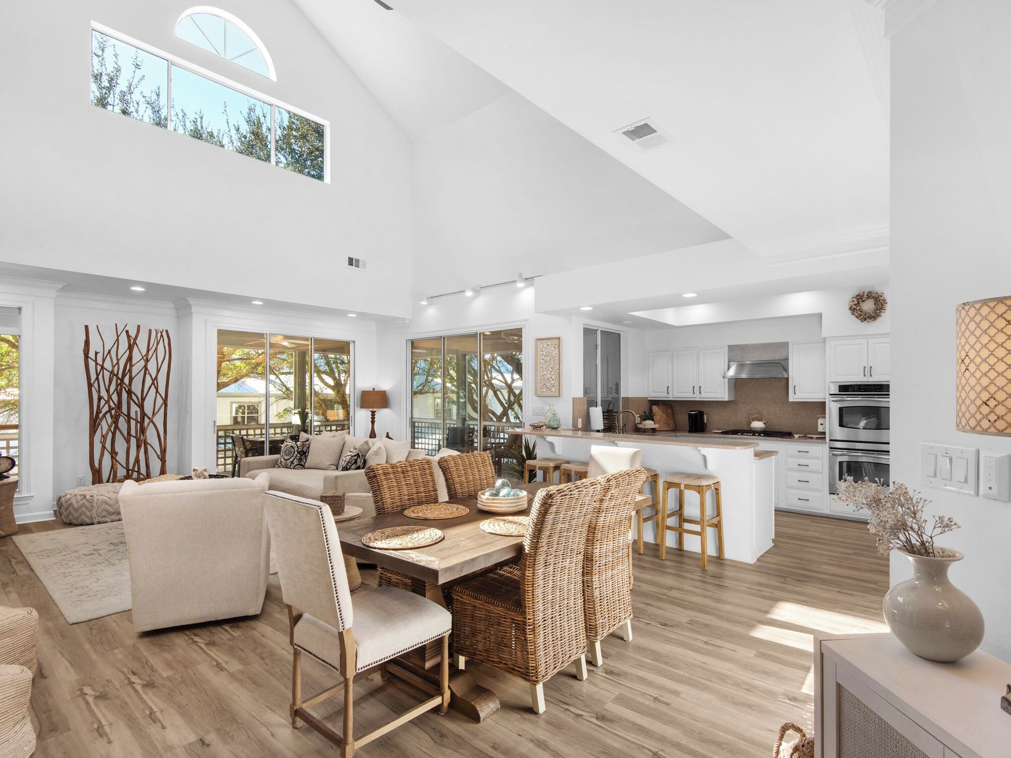A spacious living area with a dining table, wicker chairs, and a sofa.