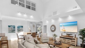 Un salón espacioso con un sofá grande, una mesa de centro y un televisor que muestra una escena de playa.
