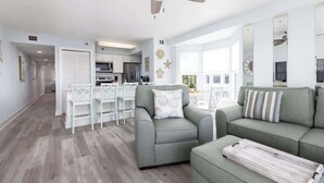 A modern living room with a grey sofa, a dining area with white chairs, and a kitchen in the background. - Spacious End Suite with Atlantic Views (Tavernier)
