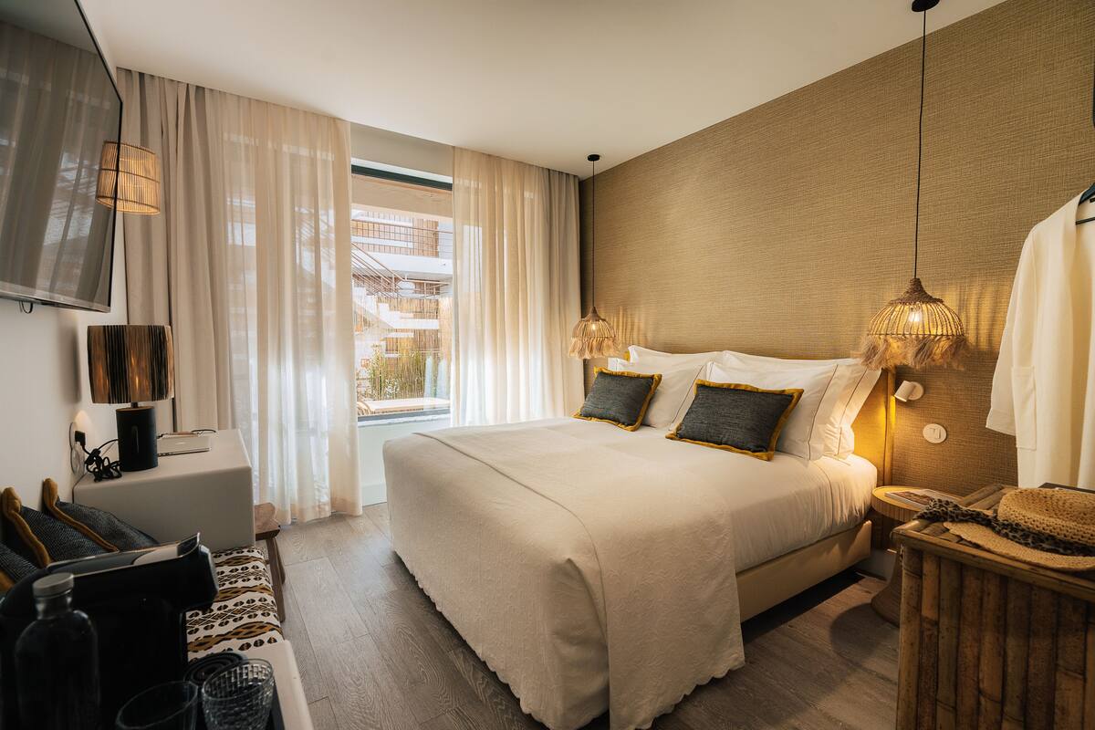 Ein modernes Hotelzimmer mit einem großen Bett, einem Schreibtisch und Blick ins Freie.