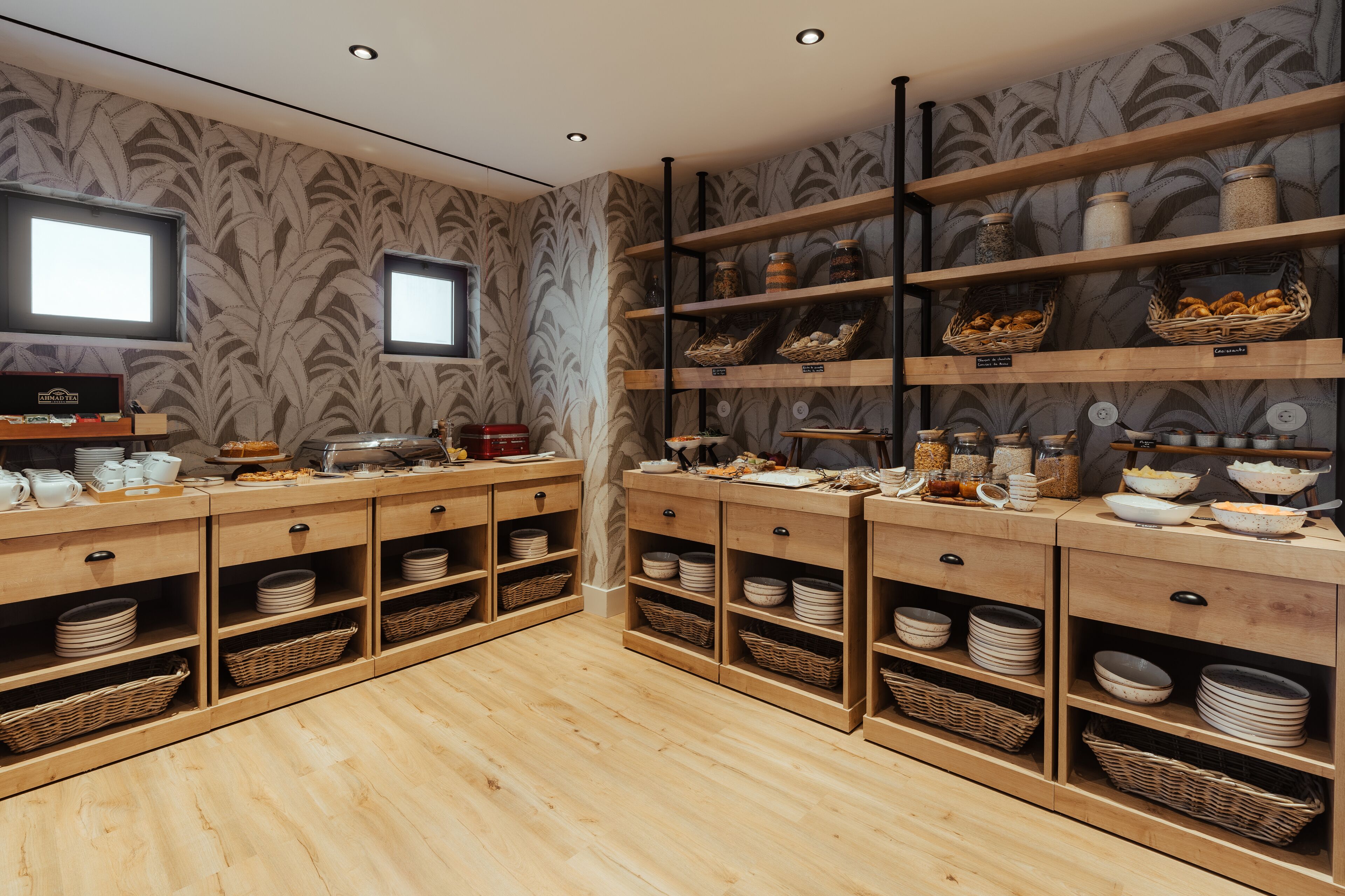A buffet setup with wooden shelves and baskets, a television, and a patterned wallpaper background.
