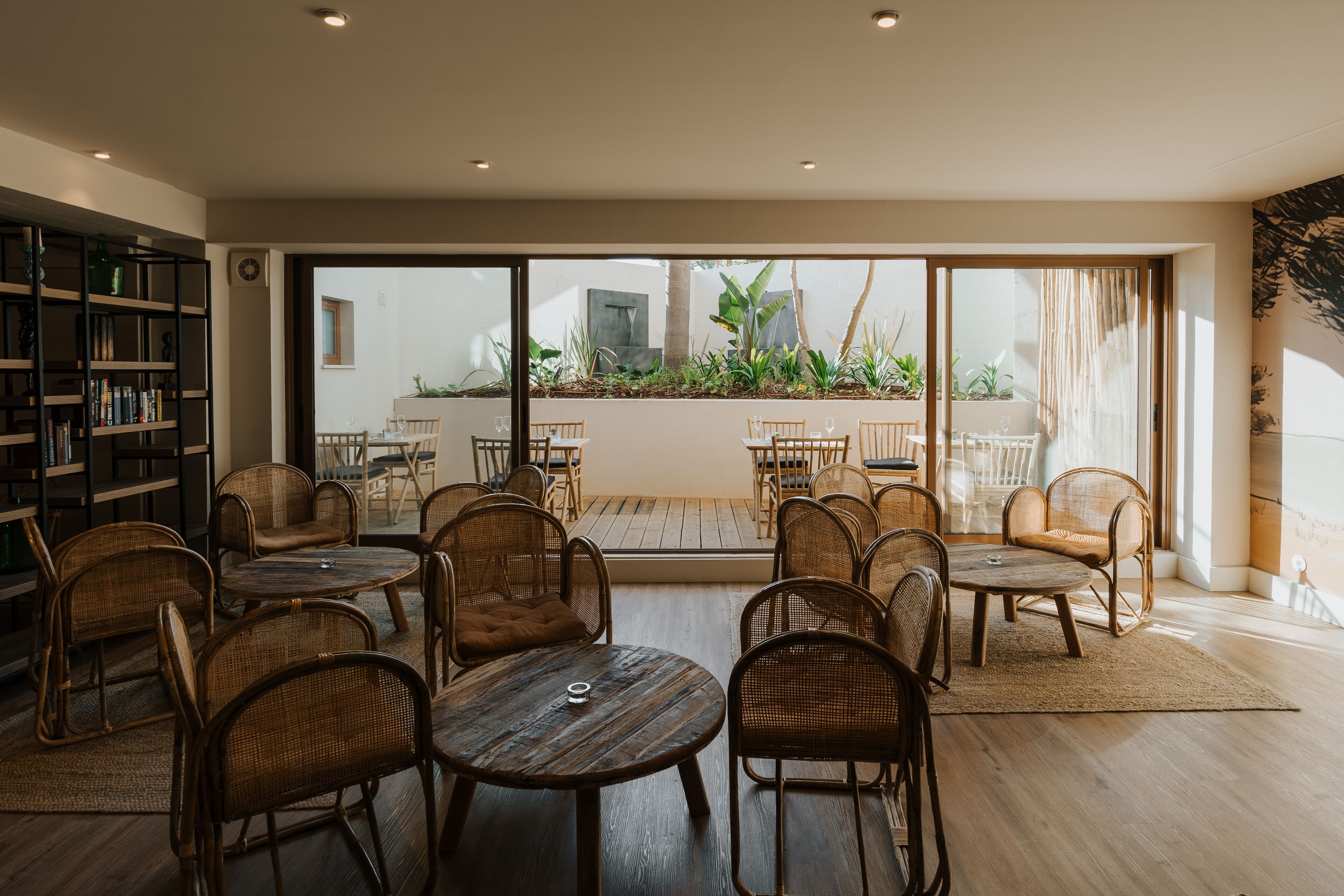 A spacious indoor seating area with wicker furniture, large windows, and a view of the outdoor patio.