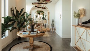 A modern interior with a round wooden table, potted plants, and a ceiling with woven baskets.