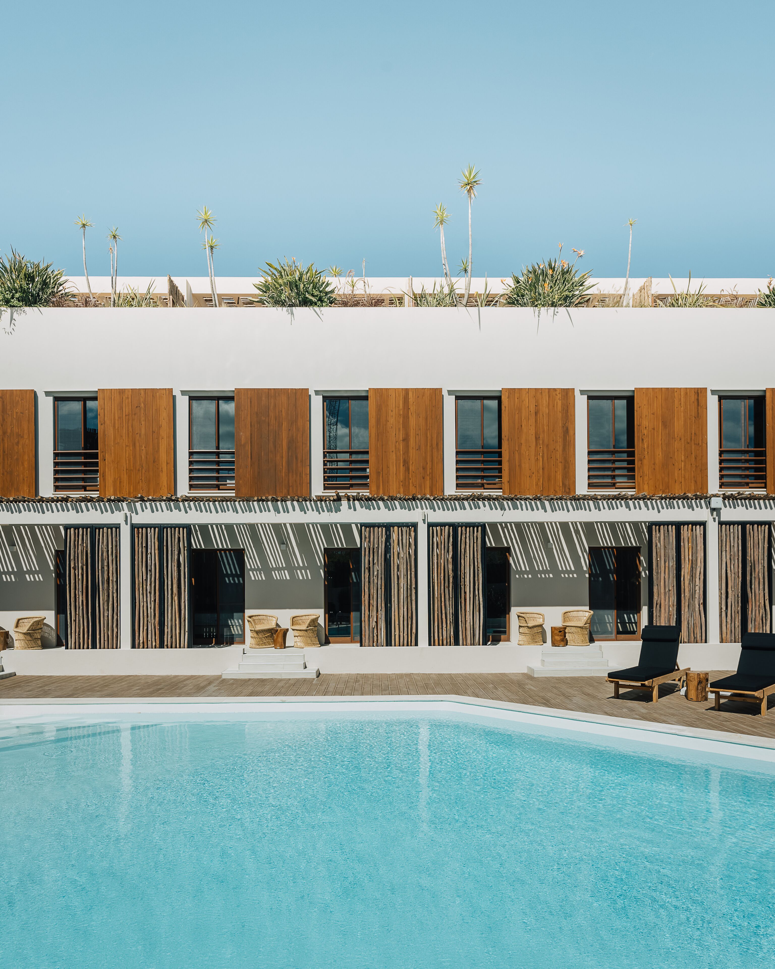 Um edifício moderno com piscina, ripas de madeira e mobiliário de vime.