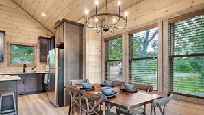 Una cucina moderna con mobili in legno, un frigorifero in acciaio inox e un'area pranzo con tavolo e sedie in legno.