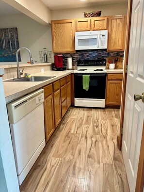 A kitchen with wooden cabinets, a microwave, a stove, and a dishwasher.