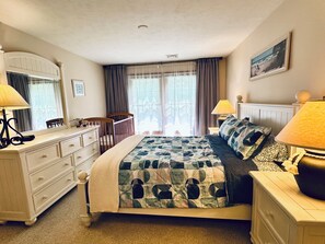A bedroom with a bed, two bedside tables, a dresser, a chair, and a window with curtains.