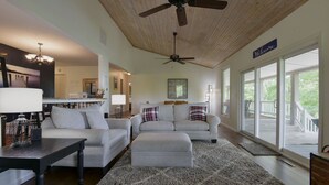 A spacious living room with a ceiling fan, large windows, and a view of the outdoors. - Large private home | Hot tub | Mins to SDC (Branson West)