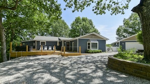 A two-story building with a gravel driveway and wooden deck. - Large private home | Hot tub | Mins to SDC (Branson West)