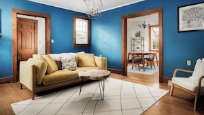 A living room with a sofa, a coffee table, and a dining area with chairs and a table.
