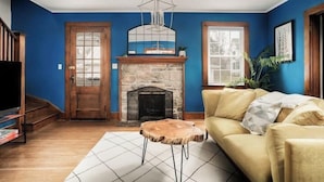 A living room with a stone fireplace, a yellow sofa, and a wooden coffee table.