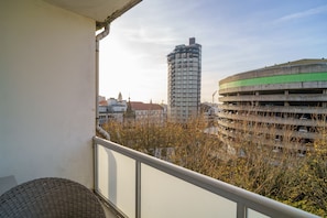 A balcony with a view of a parking garage and a tall building.