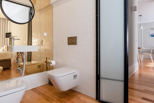 Uma casa de banho moderna com sanita, lavatório e chuveiro.