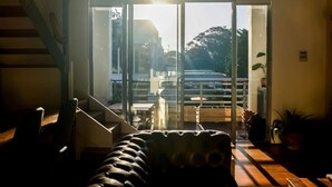 A modern interior with a staircase, a sofa, and a view through large glass doors to the outside.