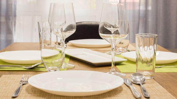 A dining table set with plates, glasses, cutlery, and a placemat. - Aleks Sunrise- Top Center ,Sea Garden (Бургас)