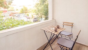 A small balcony with a wooden table and two chairs, a window overlooking a parking area. - Aleks Sunrise- Top Center ,Sea Garden (Бургас)