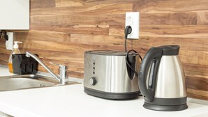 A kitchen with a wooden backsplash, a stainless steel toaster, a kettle, and a sink with a soap dispenser. - Aleks Sunrise- Top Center ,Sea Garden (Бургас)