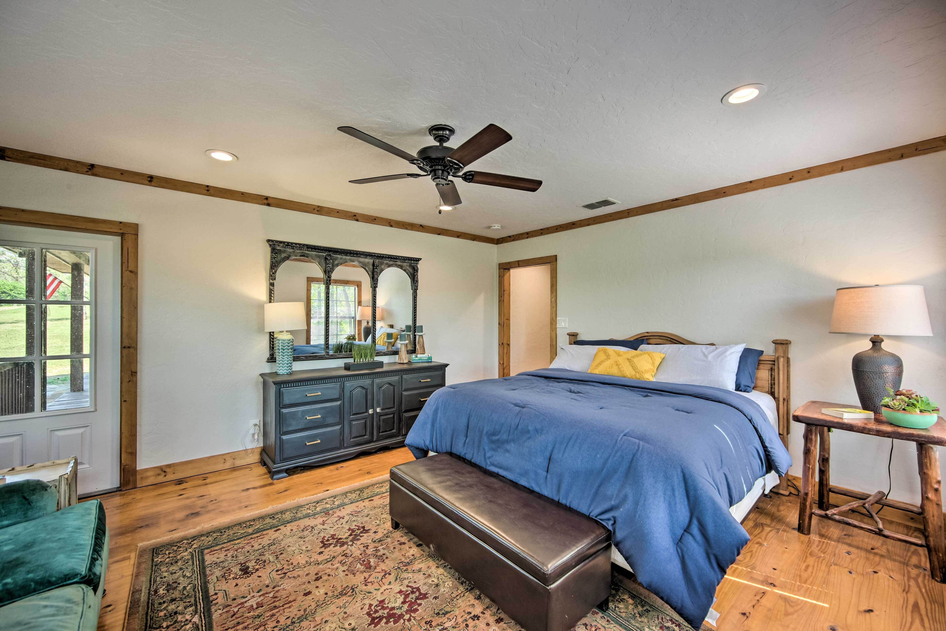 A bedroom with a large bed, a ceiling fan, a dresser, and a mirror.