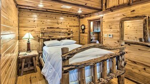 A rustic wooden room with a bed, a nightstand, a lamp, and a mirror. - ‘The Deer’ Cabin Peaceful Refuge in East Texas (Ben Wheeler)