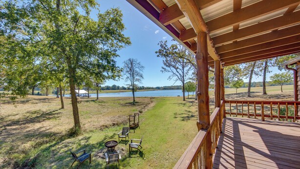A wooden deck overlooking a grassy area with a lake and trees. - ‘The Deer’ Cabin Peaceful Refuge in East Texas (Ben Wheeler)