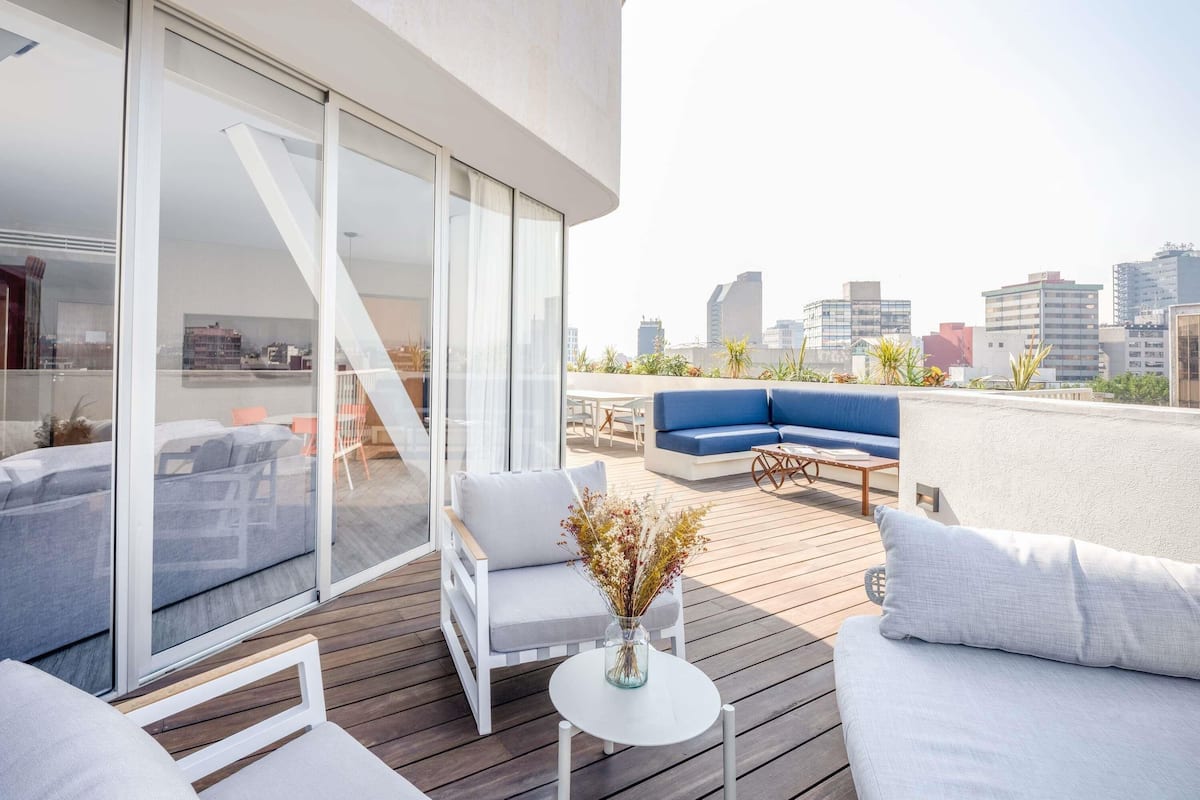 Een modern terras op het dak, met een bank, stoelen en een tafel.