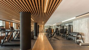A gym with treadmills, weight machines, and dumbbells.