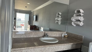A bathroom with a granite countertop, a white sink, and a large mirror. - Hiland Motel (Long Beach)