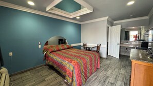 A bedroom with a bed, a desk, and a bathroom visible through an open door. - Hiland Motel (Long Beach)